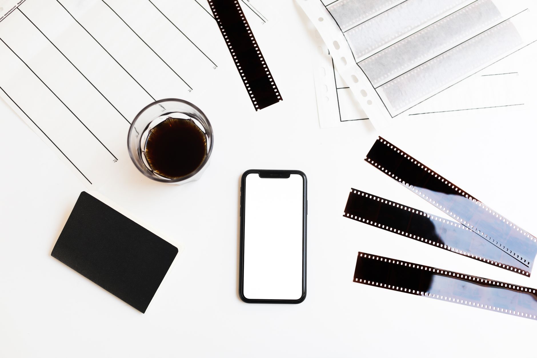 Top view of a smartphone, notebook, coffee, and film strips arranged on a table